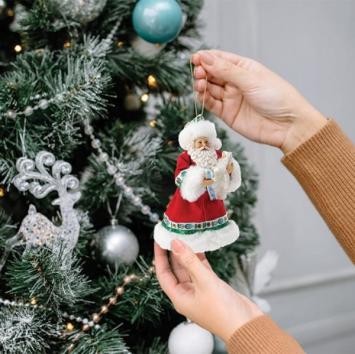 Santa houdt het kerstkindje in de armen, in de kerstboom